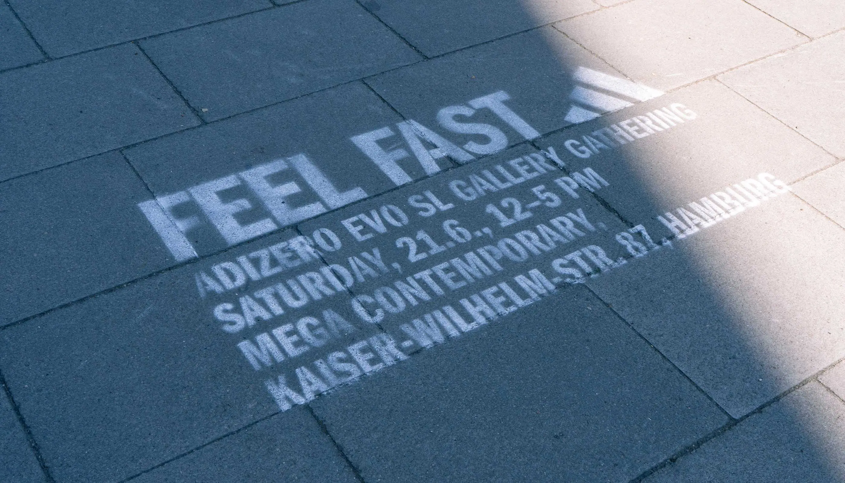White stencil graffiti on pavement reading 'FEEL FAST' with event details for Adidas Neo Evo SL Gallery Gathering in Hamburg.
