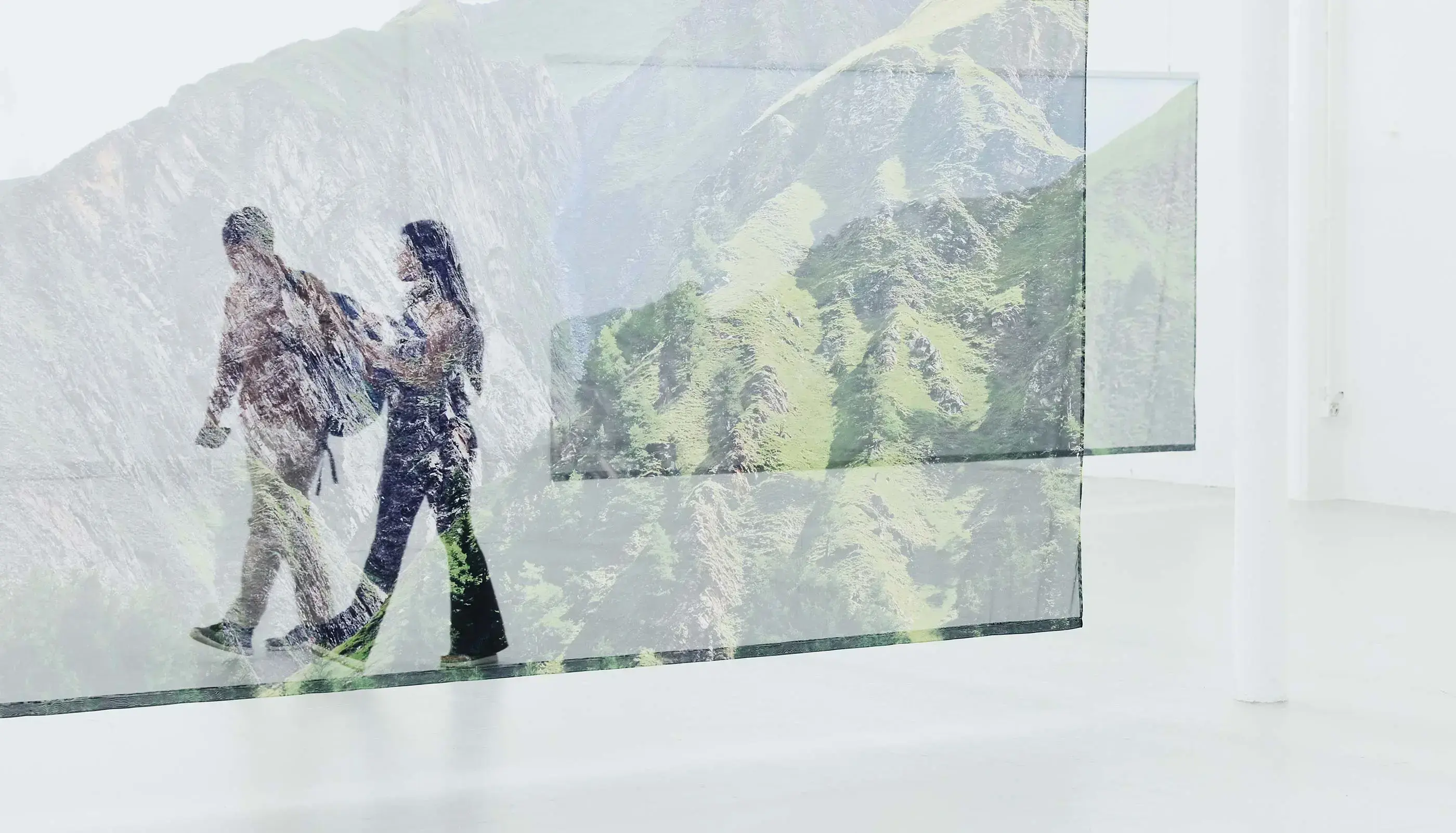 A double exposure image of a man and woman walking, blended with a scenic view of green mountains and cliffs.
